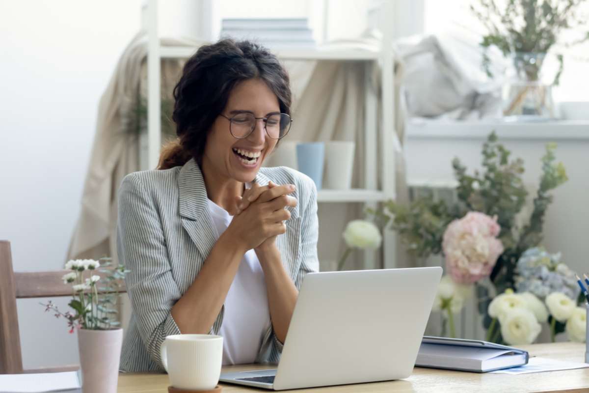 A happy young woman at a laptop enjoys working as a remote assistant
