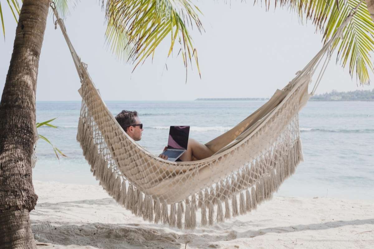 A relaxed investor in a hammock on the beach, virtual digital marketing for real estate investors concept