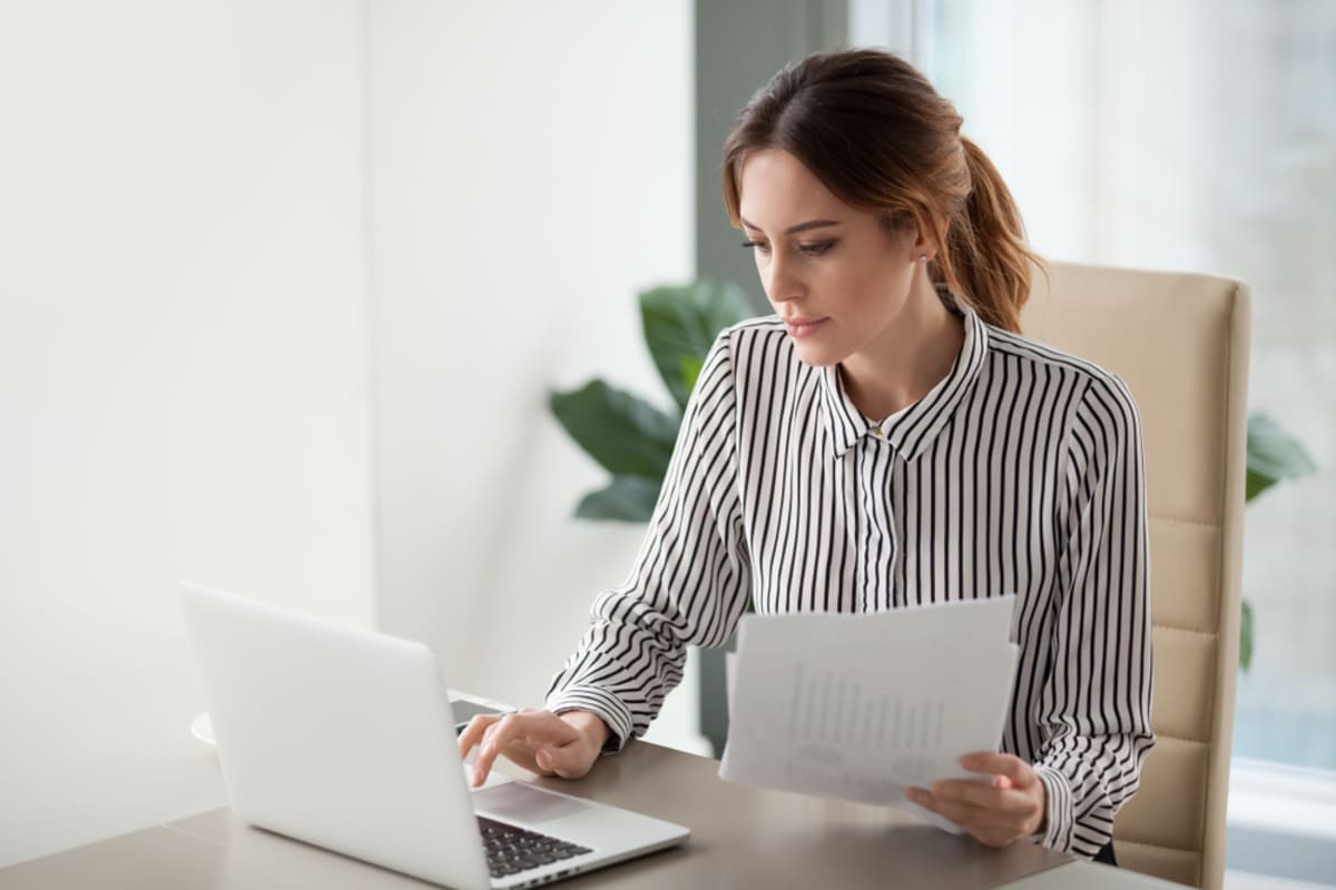 A woman at a laptop reading documents, property management virtual assistants concept
