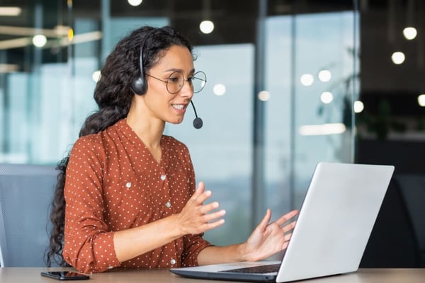 A woman with a headset working at a laptop, property maintenance services for landlords concept