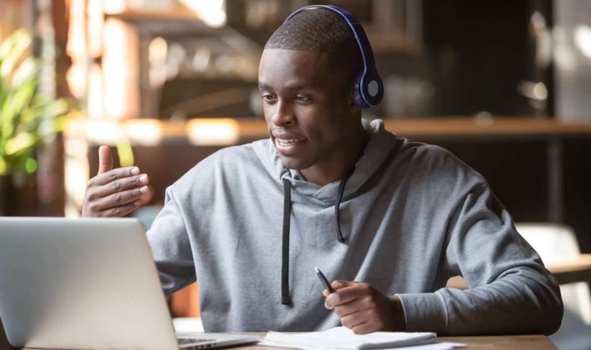 African American man in headphones making video call in cafe