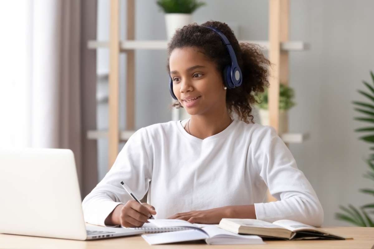 African teen girl wearing headphones study with internet chat skype teacher prepare for exam