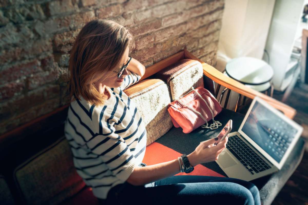 Attractive female freelancer chatting with her friends while sitting front open computer in vintage coffee shop