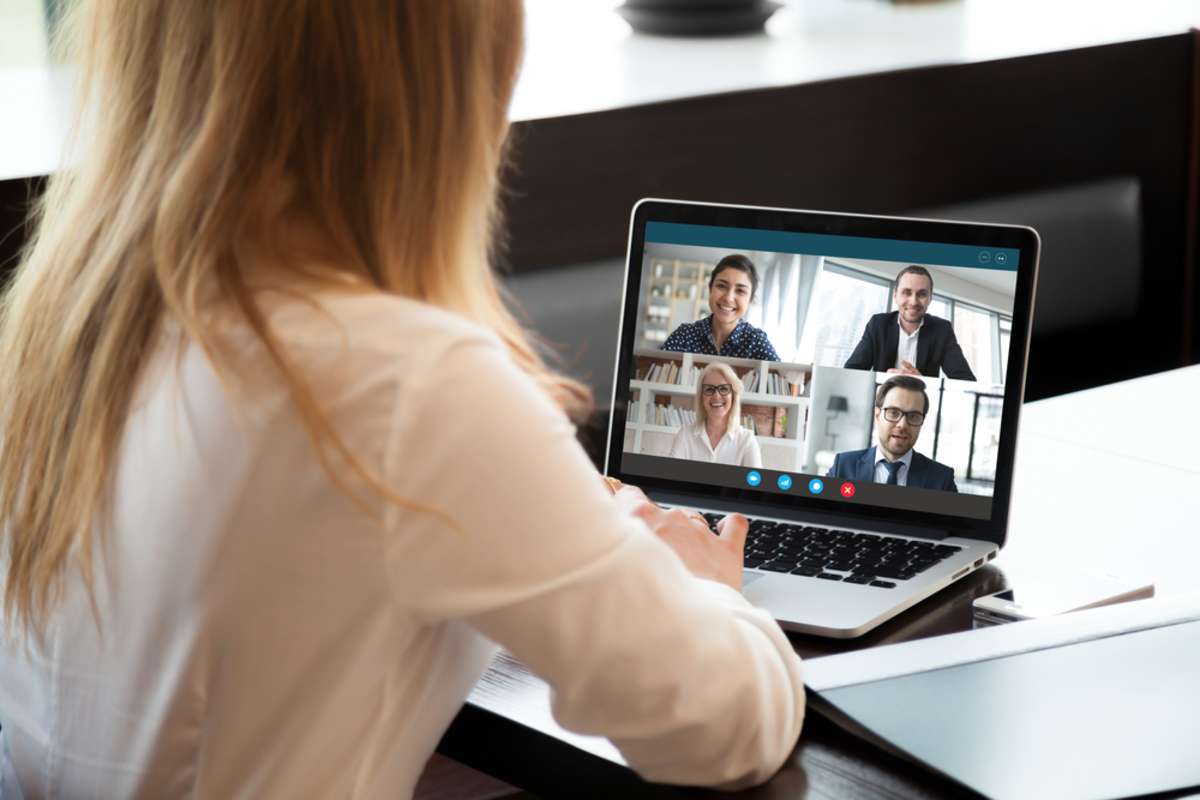 Back view of businesswoman speak using Webcam conference on laptop with diverse colleagues