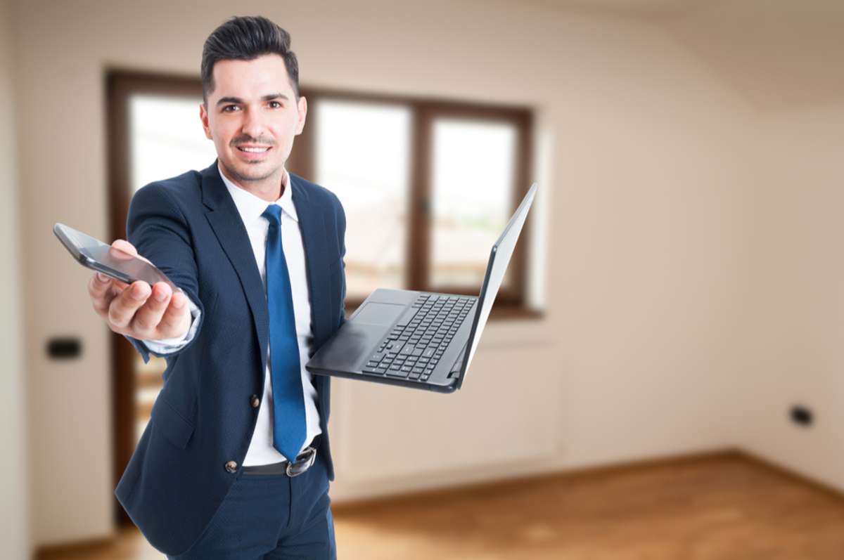Busy estate agent with laptop and smartphone renting a new property as multitasking concept