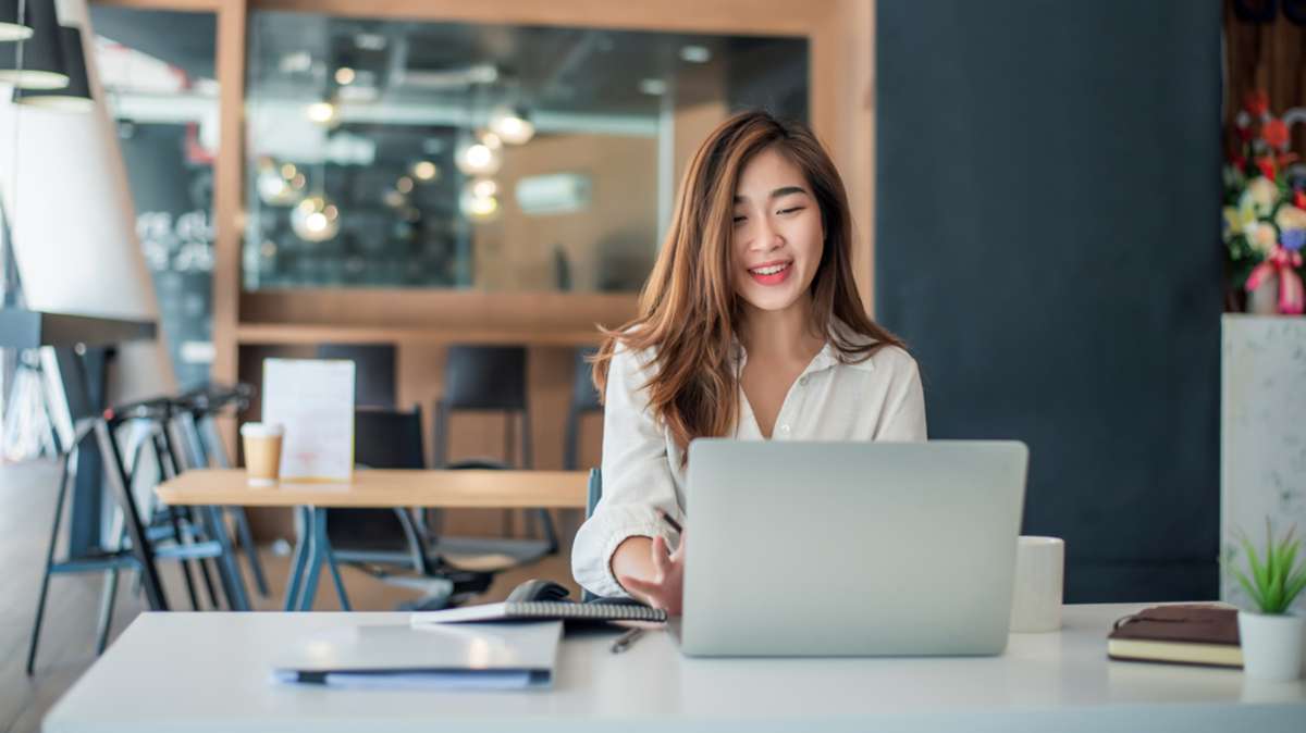 Charming asian businesswoman sitting working on laptop in office