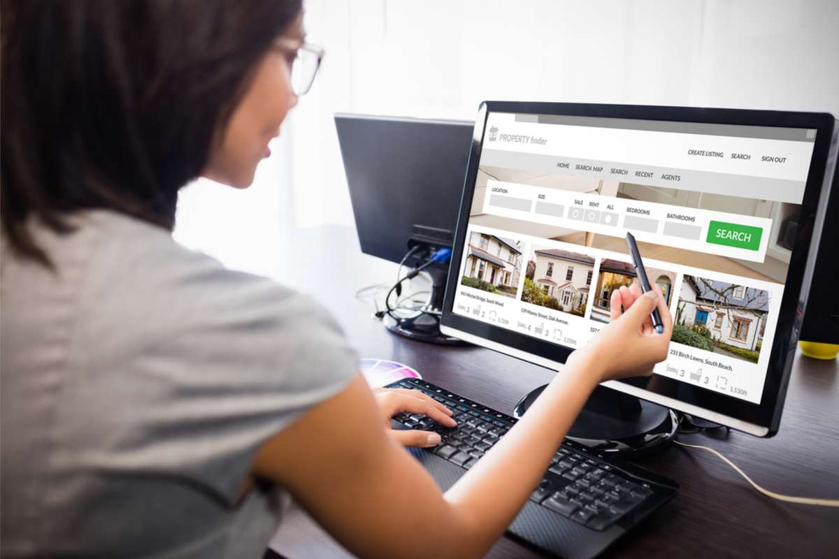 Composite image of property web site against woman watching her computer