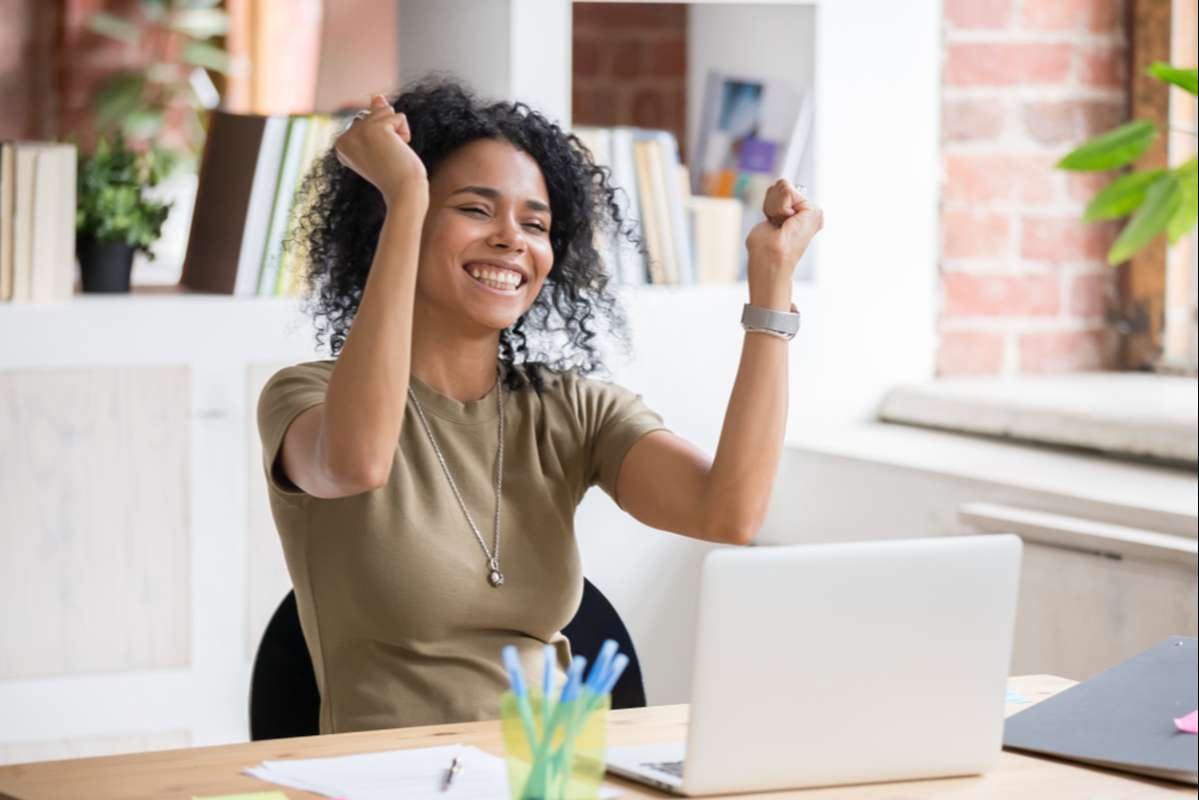 Excited african American woman sit at desk feel euphoric win online lottery