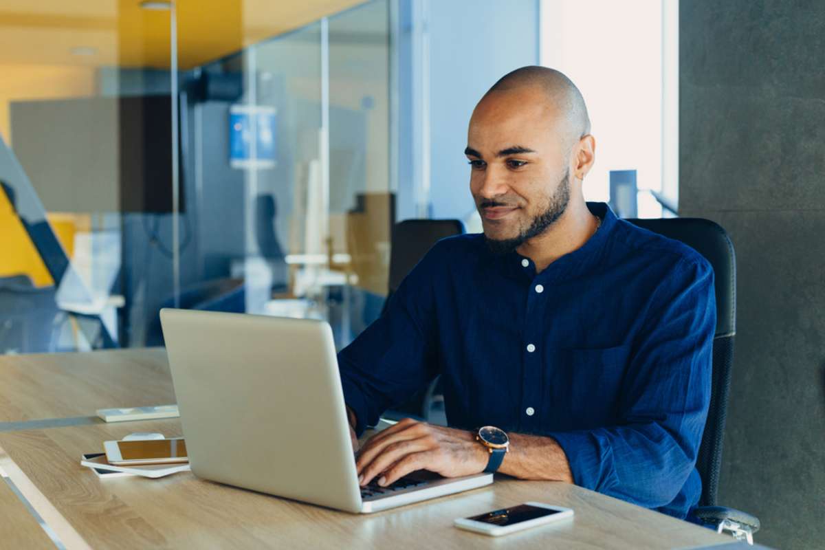 Happy african american businessman entrepreneur startup owner stand in modern office looking at camera