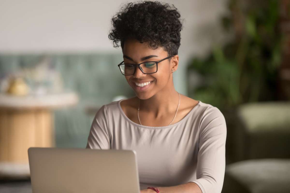 Happy african american woman worker using laptop work study at computer in loft office or cafe