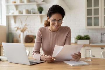 Happy millennial hispanic lady review printed paper documents financial reports satisfied with good state of business