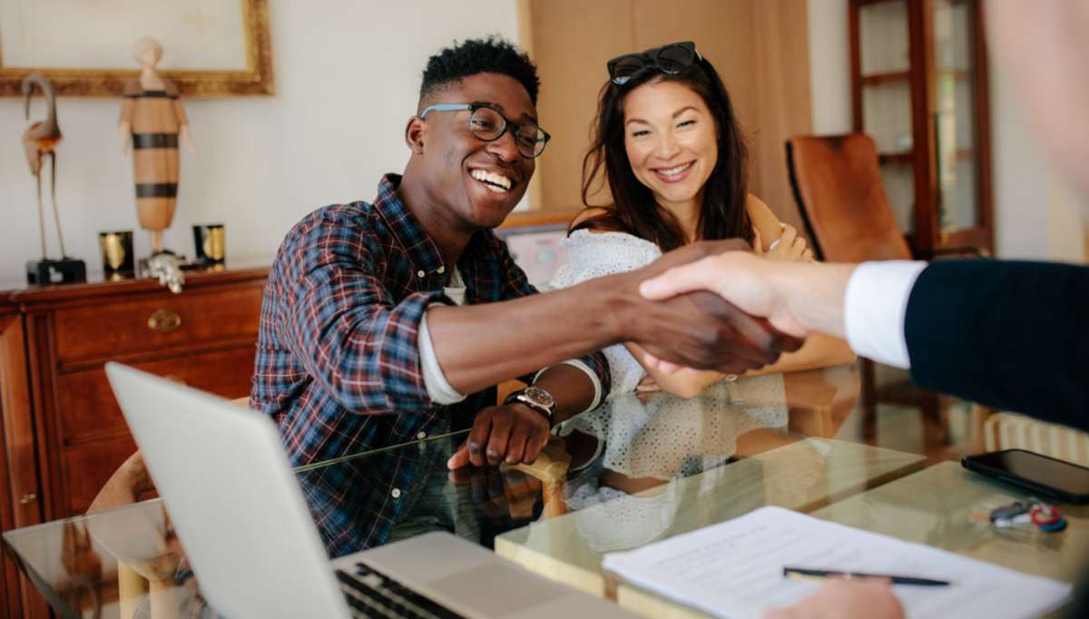 Happy property owners shaking hands with real estate broker after a deal