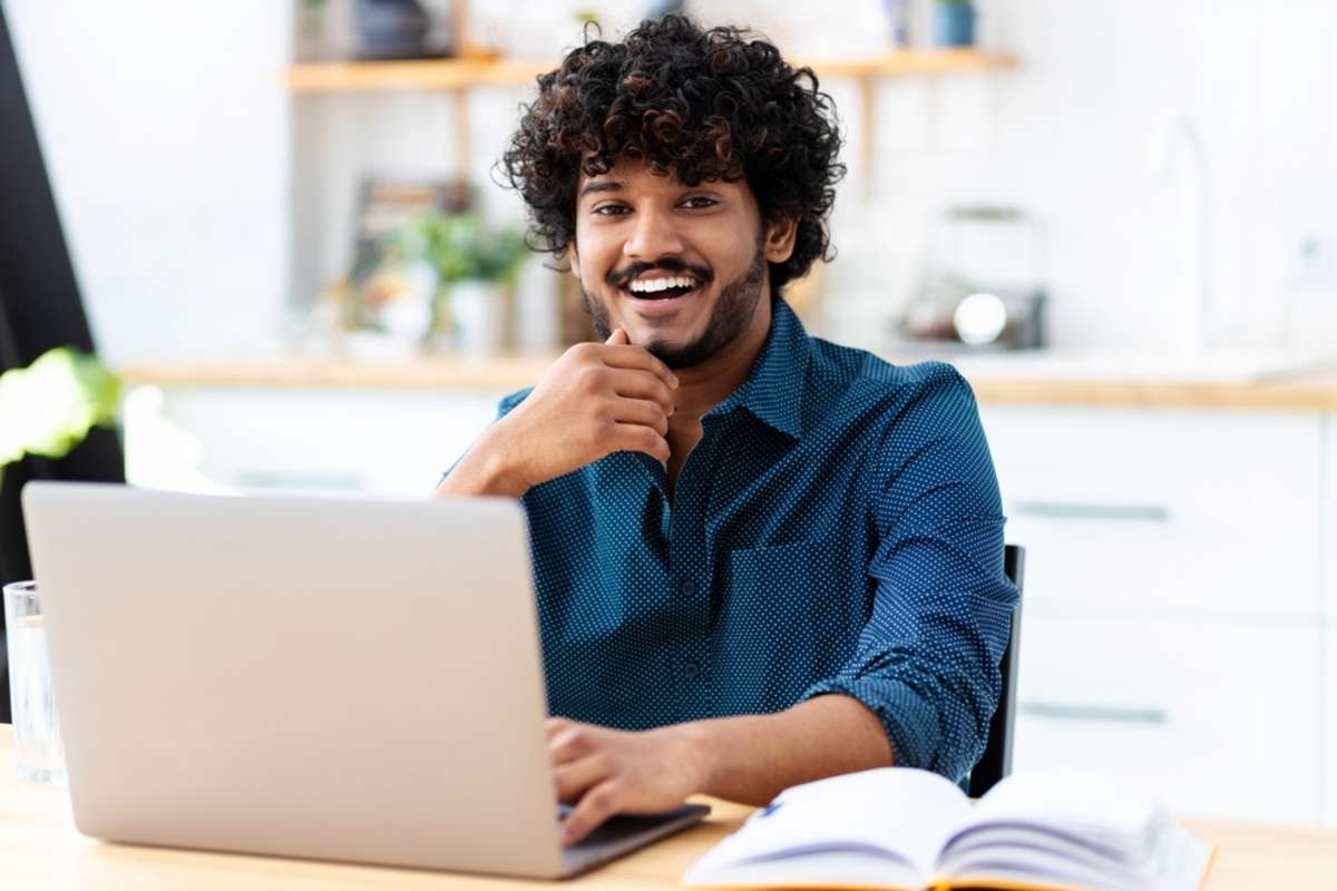 Happy young man working at a computer, property management virtual assistant concept
