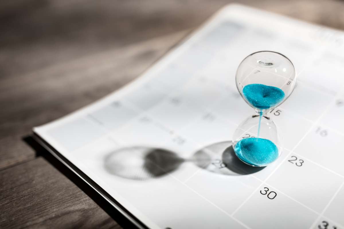 Hour glass on calendar concept for time slipping away for important appointment date
