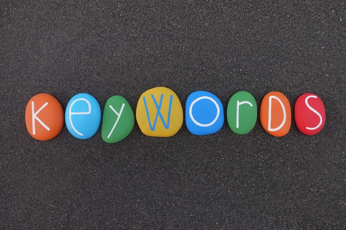 Keywords text composed with multi colored stones over black volcanic sand