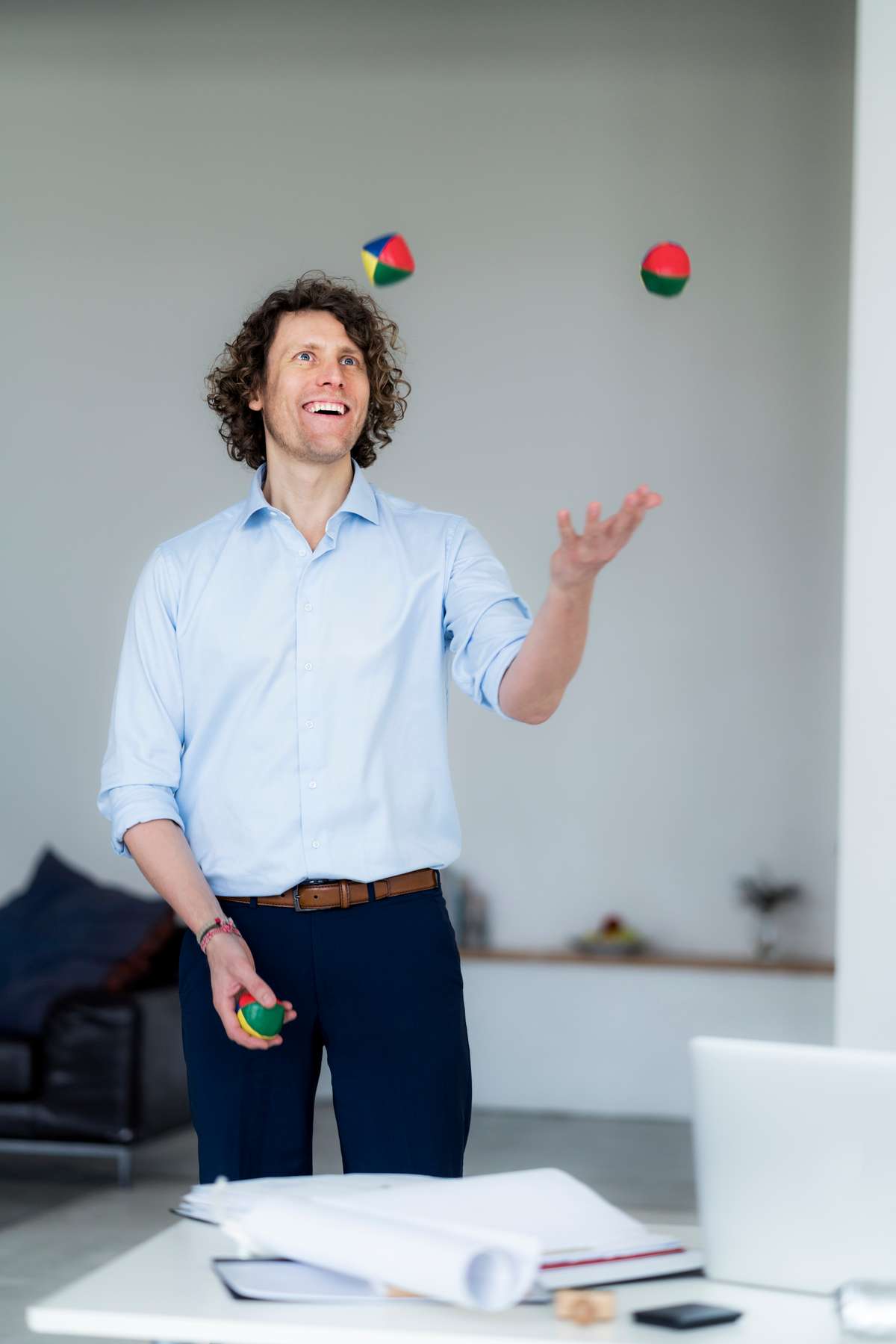 Laughing businessman juggling balls in his office