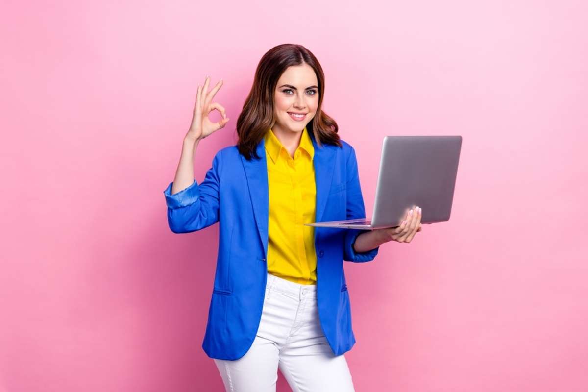 Photo of young business lady wear yellow shirt blue jacket hold netbook show okey sign