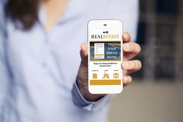 A woman holds a phone with a mobile real estate website design. 