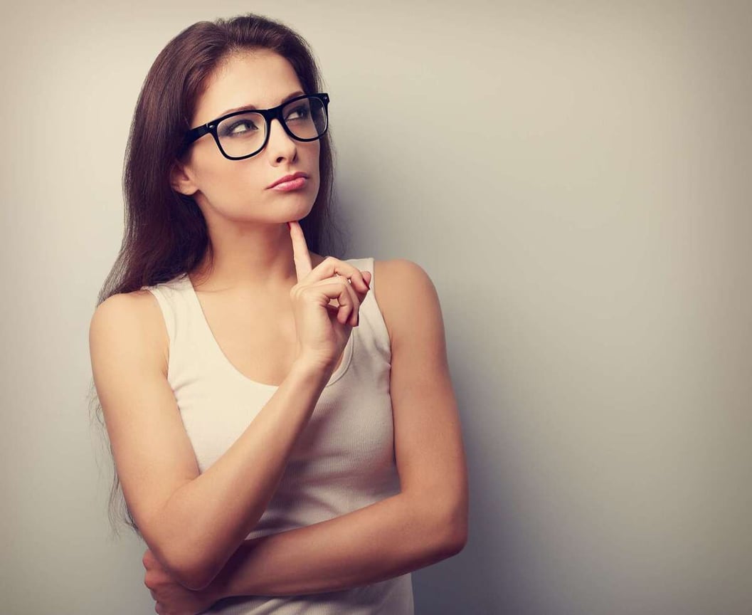 Serious fun thinking young woman looking up on empty copy space
