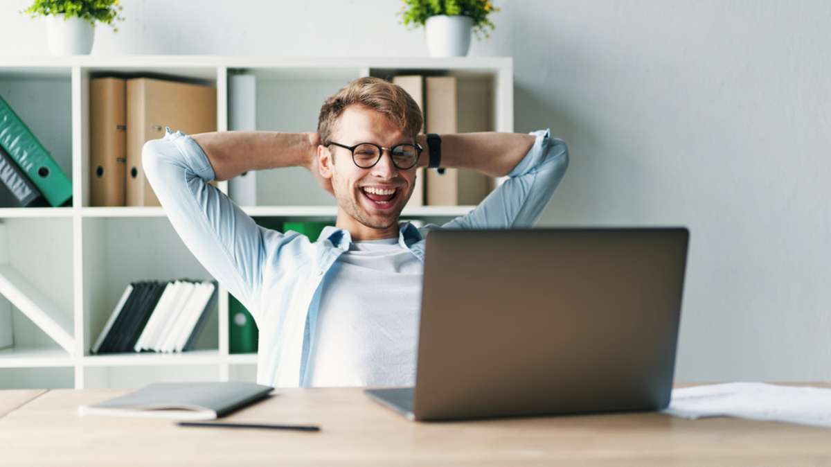 Smiling man looking at the laptop, success for a virtual assistant for property management concept