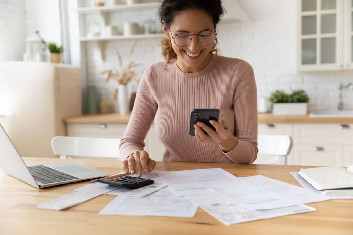 Smiling young 30s woman in eyewear looking at smartphone screen, feeling satisfied with fast secure online service