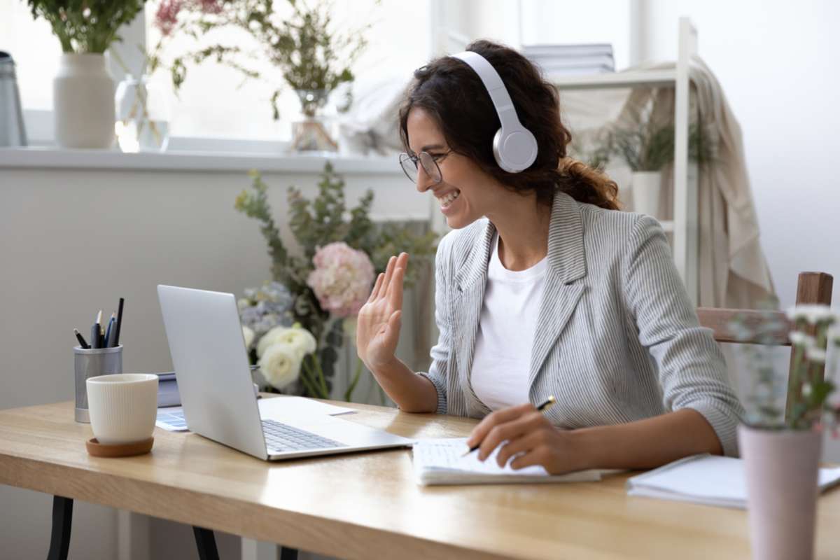 Smiling young Caucasian woman in headphones take online educational course or training on laptop-1