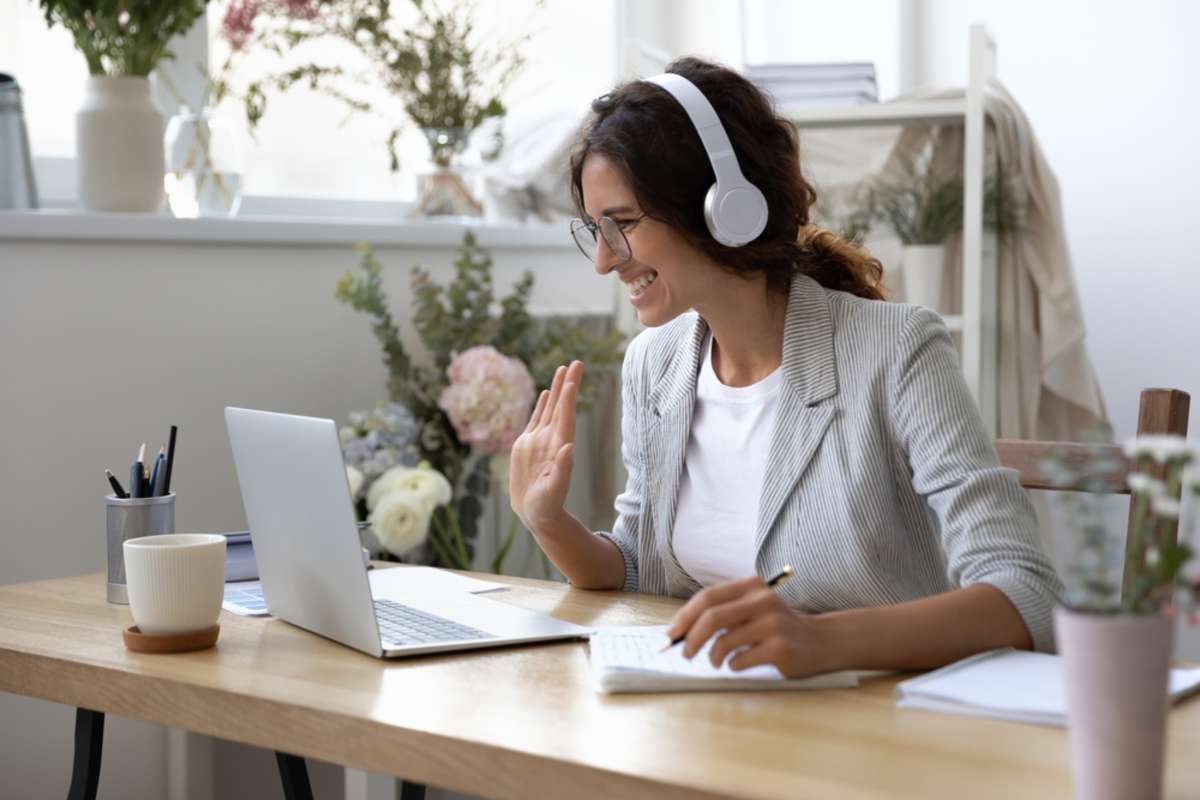 Smiling young Caucasian woman in headphones take online educational course or training on laptop