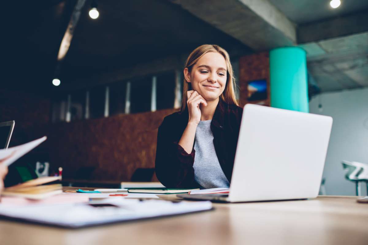 A real estate marketing assistant works at a laptop. 