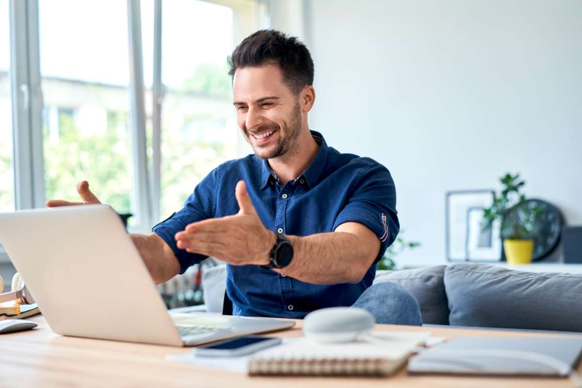 Successful young man looking on laptop while working at home office