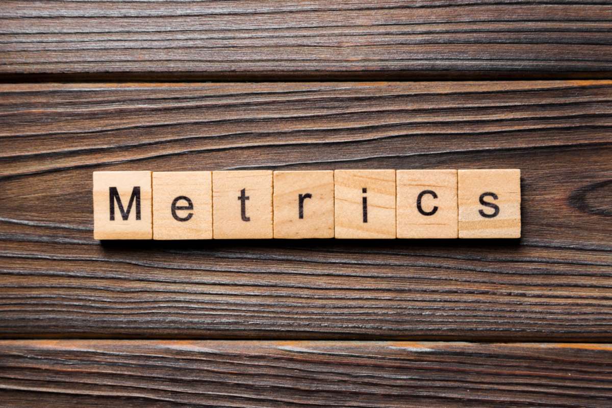 The word metrics is spelled in wooden blocks, measuring success for remote team members