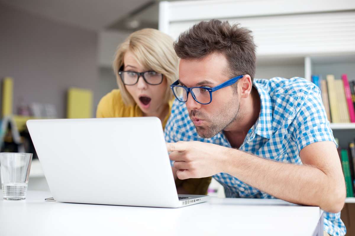 Two surprised people look at a laptop and find a virtual property management solution. 