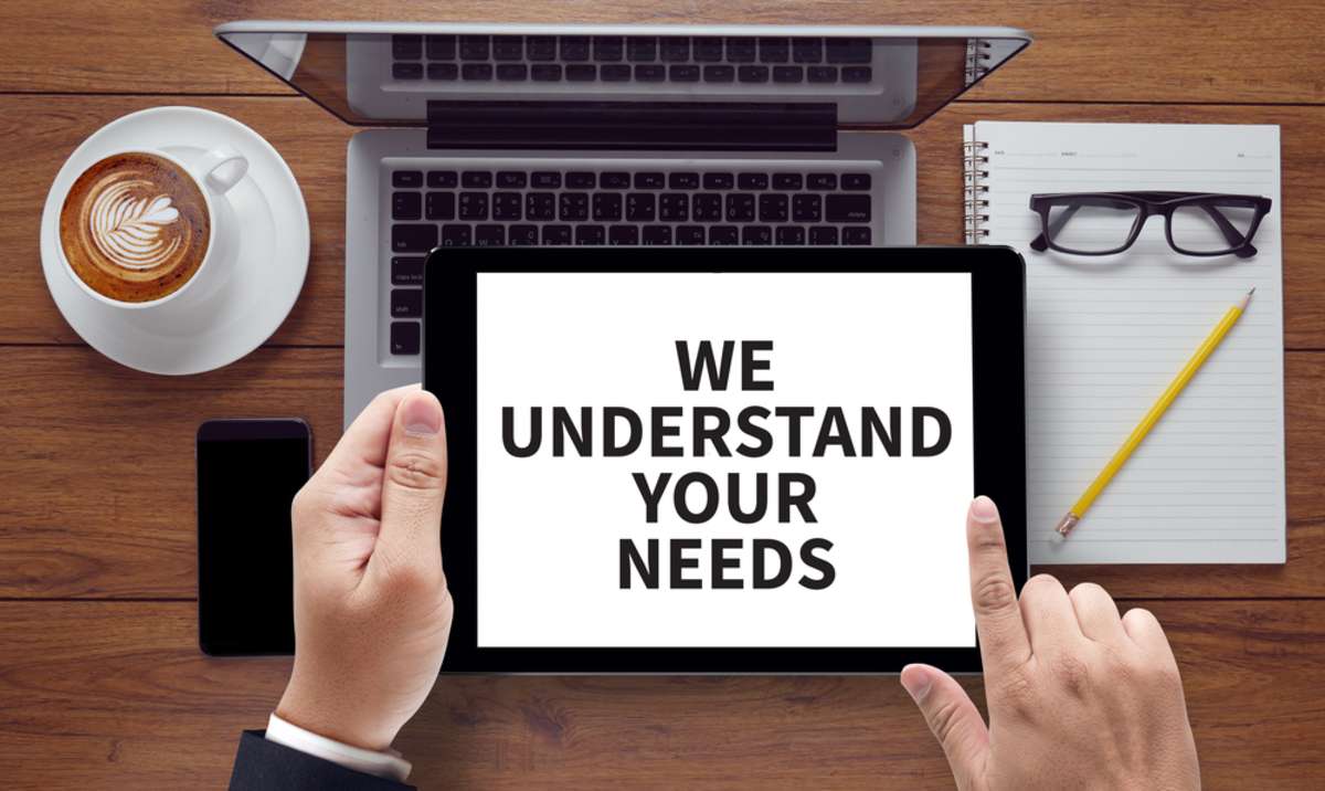 WE UNDERSTAND YOUR NEEDS, on the tablet pc screen held by businessman hands - online, top view