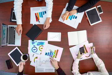 Top view of business meeting desk with charts and laptop.