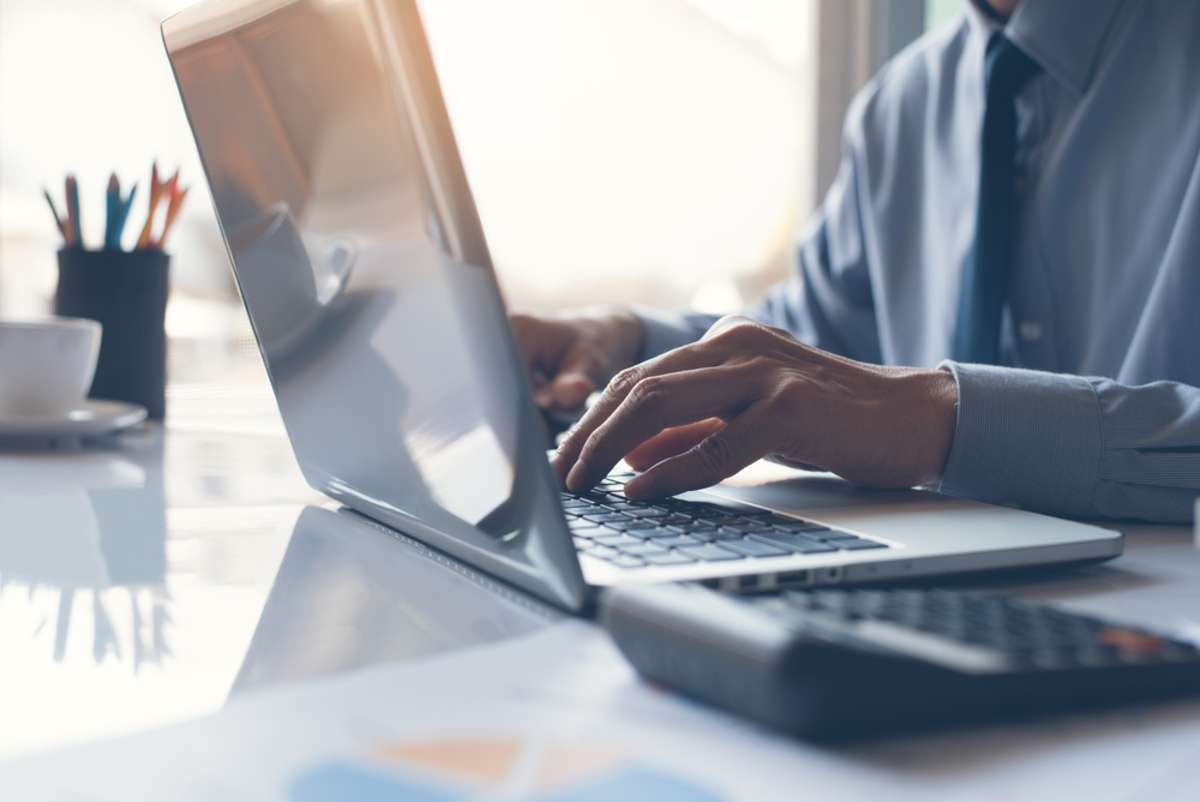 Man working on laptop computer as a property management virtual assistant.