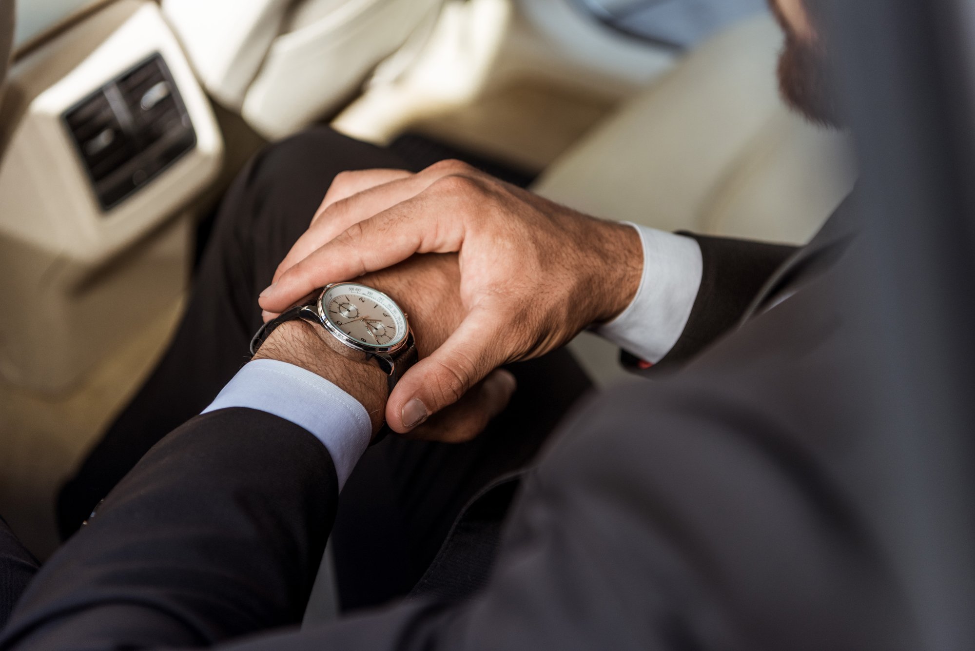 Cropped image of businessman checking time on wristwatch in car