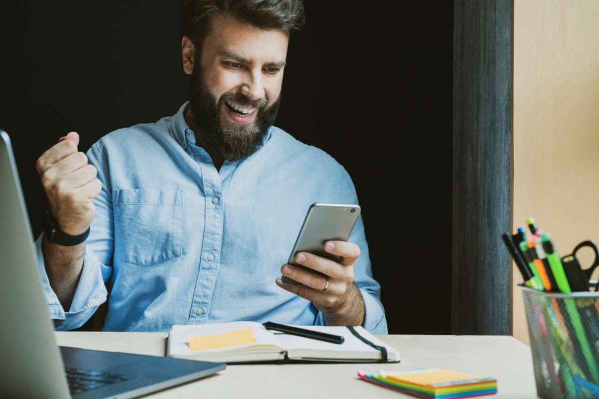 Man rejoices in victory while looking at screen of smartphone