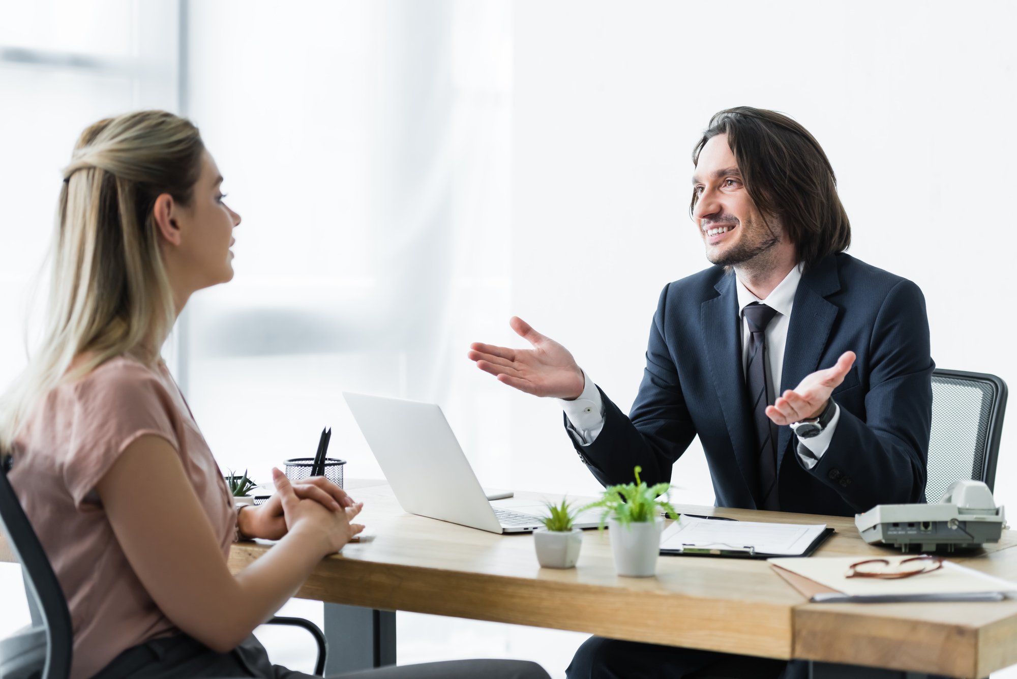 Selective focus of cheerful businessman talking with client in office