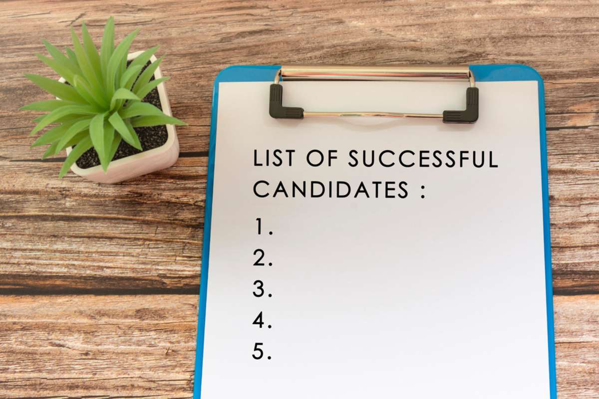 List of Successful Candidates on blue clip board, selecting real estate virtual assistants concept. 