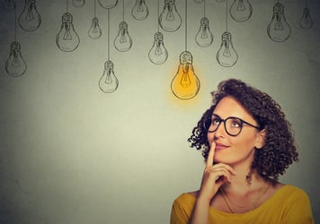 A woman looks at lightbulbs and thinks, how to post a virtual assistant job description. 