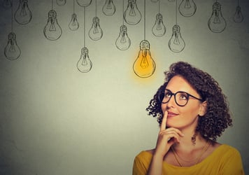 A woman looks at lightbulbs and thinks, how to post a virtual assistant job description.