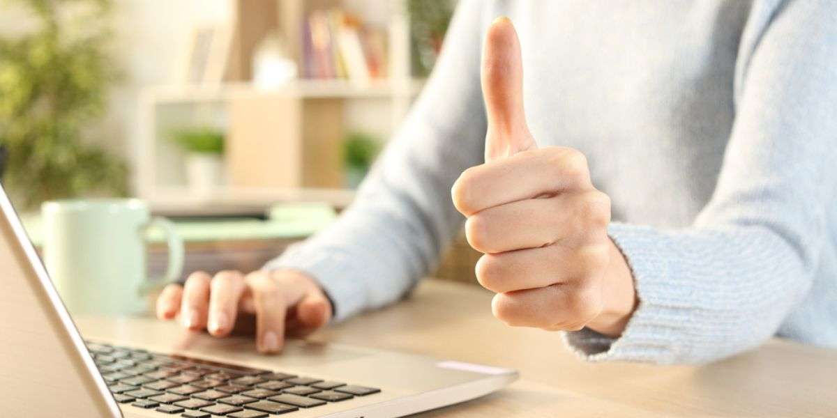 Close up of girl hands gesturing thumbs up using laptop on a desk at home